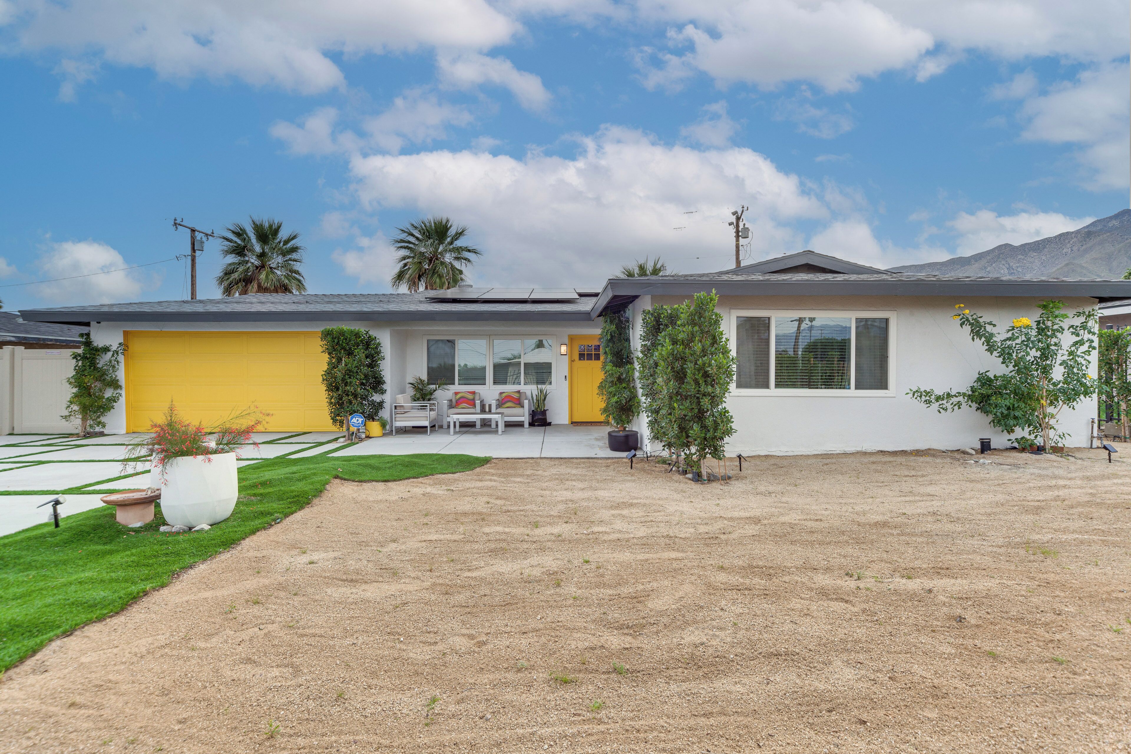 A modern house with a yellow garage, a well-maintained lawn, and a clear sky.
