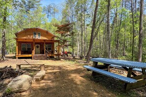 Eine Holzhütte mit Veranda, Picknicktisch und bewaldeter Umgebung.