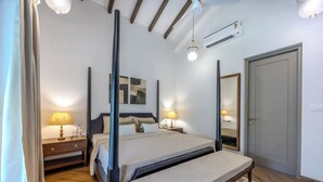 Un dormitorio moderno con cama con dosel, lámparas de noche, suelo de madera y un espejo grande.