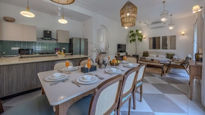 Una cocina moderna con comedor, que presenta una isla grande, lámparas colgantes y vistas al salón.