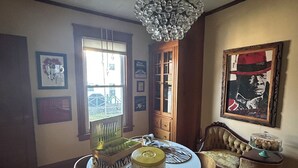 Un comedor con candelabro, mesa de madera, sillas y una ventana con persianas.