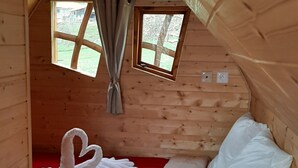 Une pièce chaleureuse, aménagée dans un chalet en bois, avec un lit, deux fenêtres et une couverture rouge.