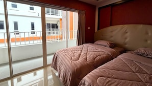 A hotel room with two beds, a large window, and a view of a building outside. - Modern Studio With Balcony and Pool - Pratumnak Hill (Pattaya)