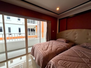 A hotel room with two beds, a large window, and a view of a building outside. - Modern Studio With Balcony and Pool - Pratumnak Hill (Pattaya)