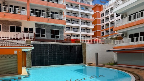 A swimming pool with the words "New Nordic" on the water, surrounded by a multi-story building with balconies. - Modern Studio With Balcony and Pool - Pratumnak Hill (Pattaya)