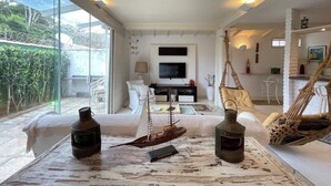 A spacious living area with a large window, a television, and a hammock. - House in Búzios (Geribá) a few meters from the beach. (Armação dos Búzios)