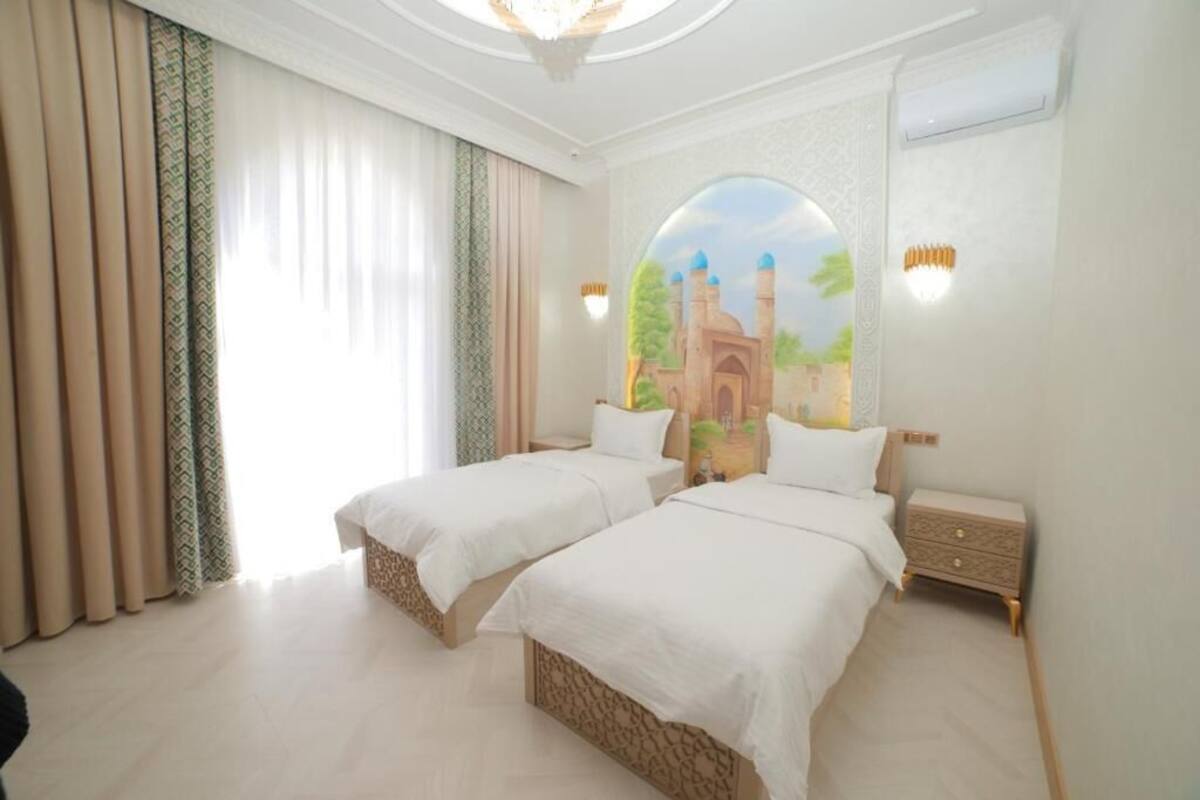 A hotel room with two beds, a large window with curtains, a wall mural, and a nightstand.