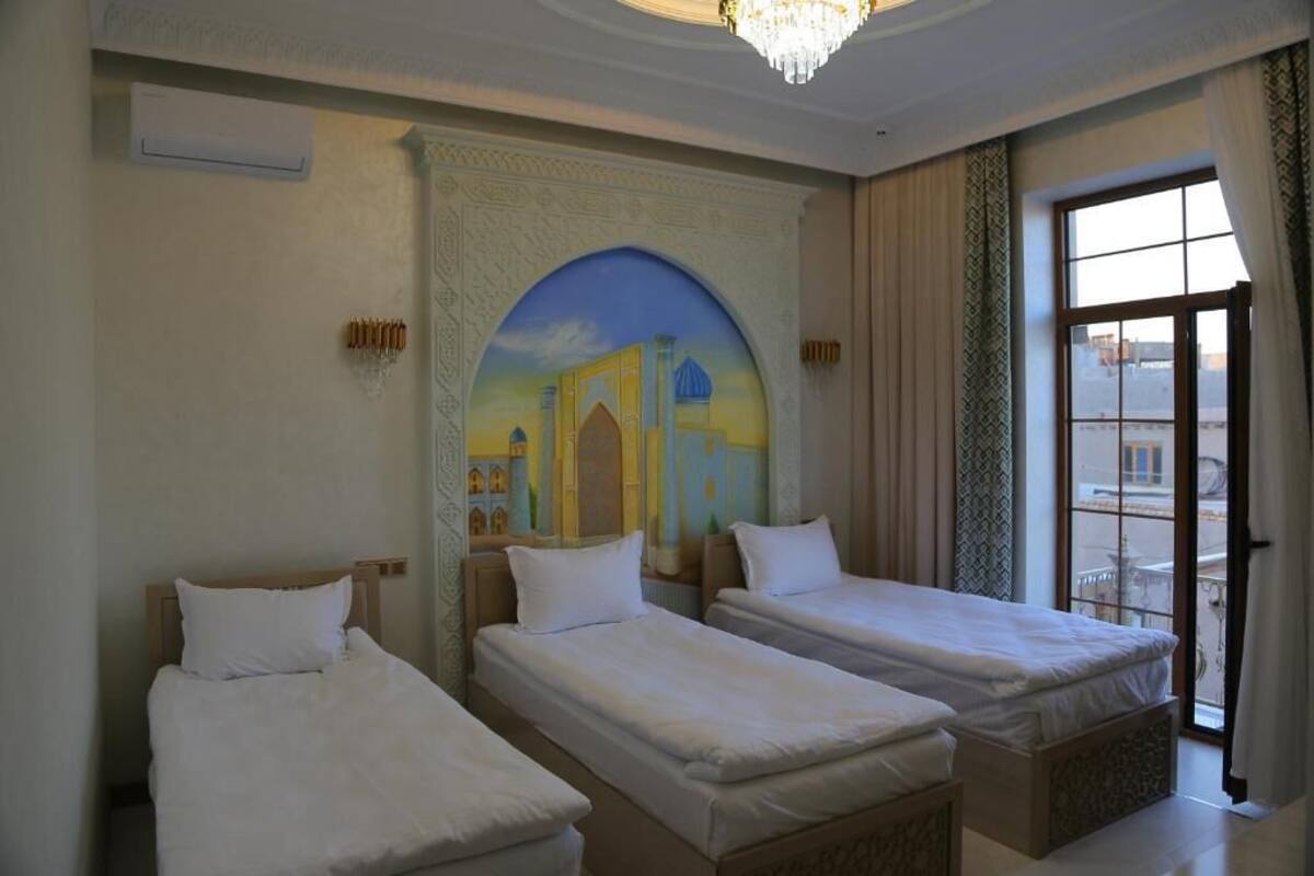 A hotel room with two single beds, a large window with a view, and a decorative archway with a painting.