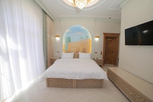A bedroom with a large bed, a TV mounted on the wall, and a decorative archway.