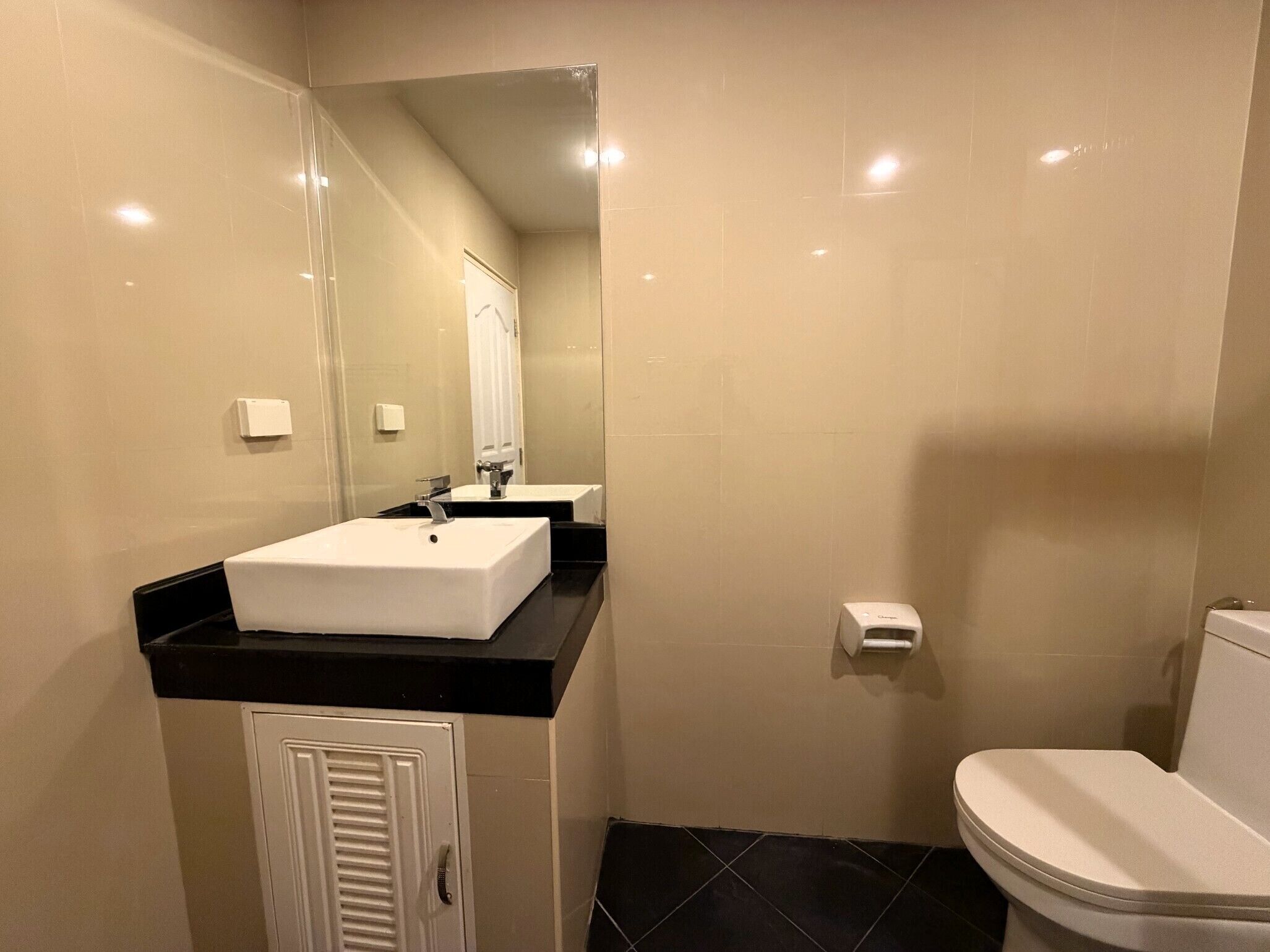 A bathroom with a white sink, black countertop, and a toilet.