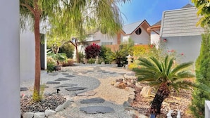 A garden pathway with stepping stones, palm trees, and various plants. - Rabbit Villa Bangsaray (Sattahip)