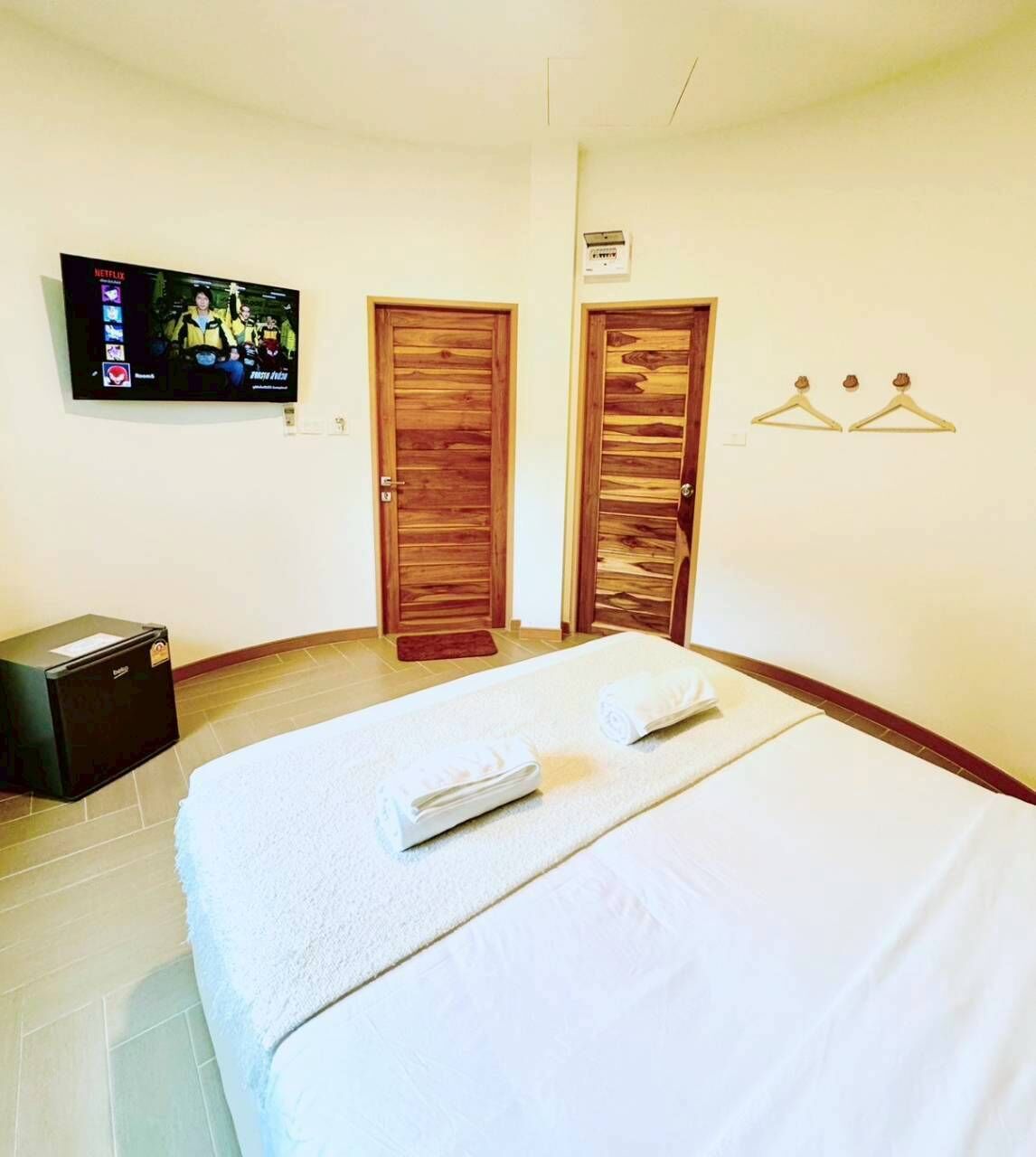 Una habitación de hotel con una cama, un televisor en la pared y dos puertas de madera.