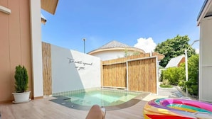 A person relaxing by a pool with a book, a colorful inflatable ring, and a bamboo fence. - Rabbit Villa Bangsaray (Sattahip)