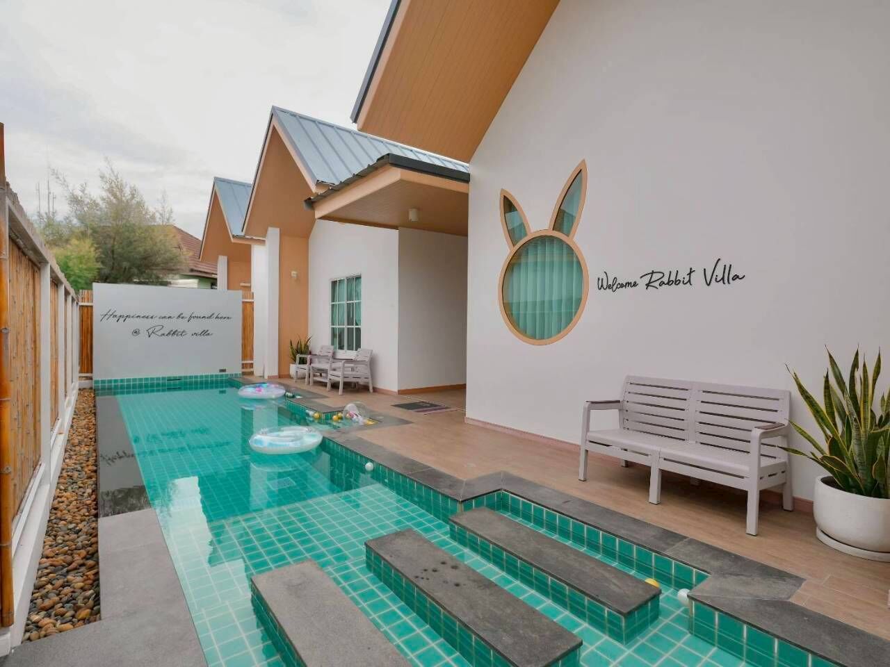 Ein moderner Poolbereich mit einer Bank und einem Schild mit der Aufschrift 'Welcome Rabbit Villa'.