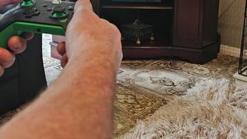 A person holding a green Xbox controller in front of a television displaying the Xbox logo.