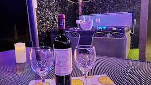 An outdoor dining area with a table set for two, featuring a bottle of wine and two glasses. - Hot Tub Cottage Near Mourne Mountains | Sleeps 6 + Infants, Pet-Friendly (Ballyward)
