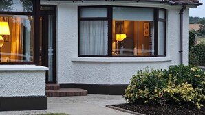 A two-story house with a white exterior, a dark roof, and a small front garden. - Hot Tub Cottage Near Mourne Mountains | Sleeps 6 + Infants, Pet-Friendly (Ballyward)