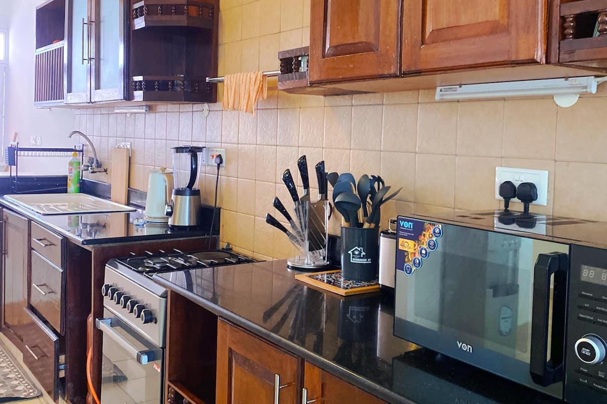 Una cocina con armarios de madera, estufa, horno, microondas y fregadero.