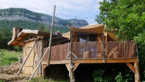 Un chalet rustique en bois doté d’un balcon, entouré de verdure et de montagnes.