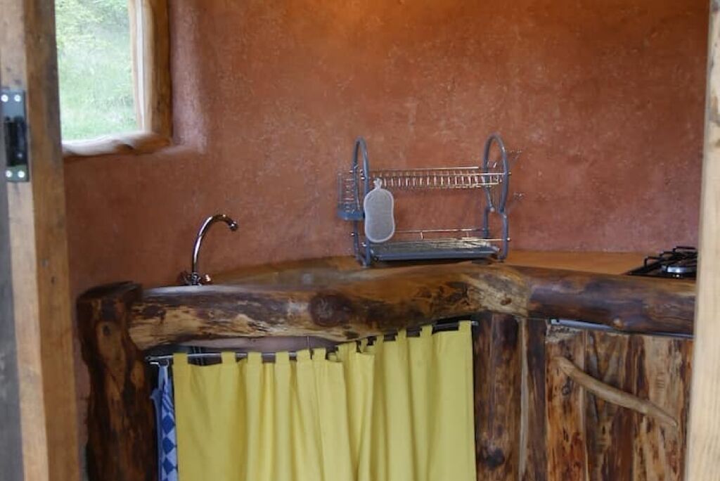 A rustic kitchen with a wooden countertop, a sink, and a window.