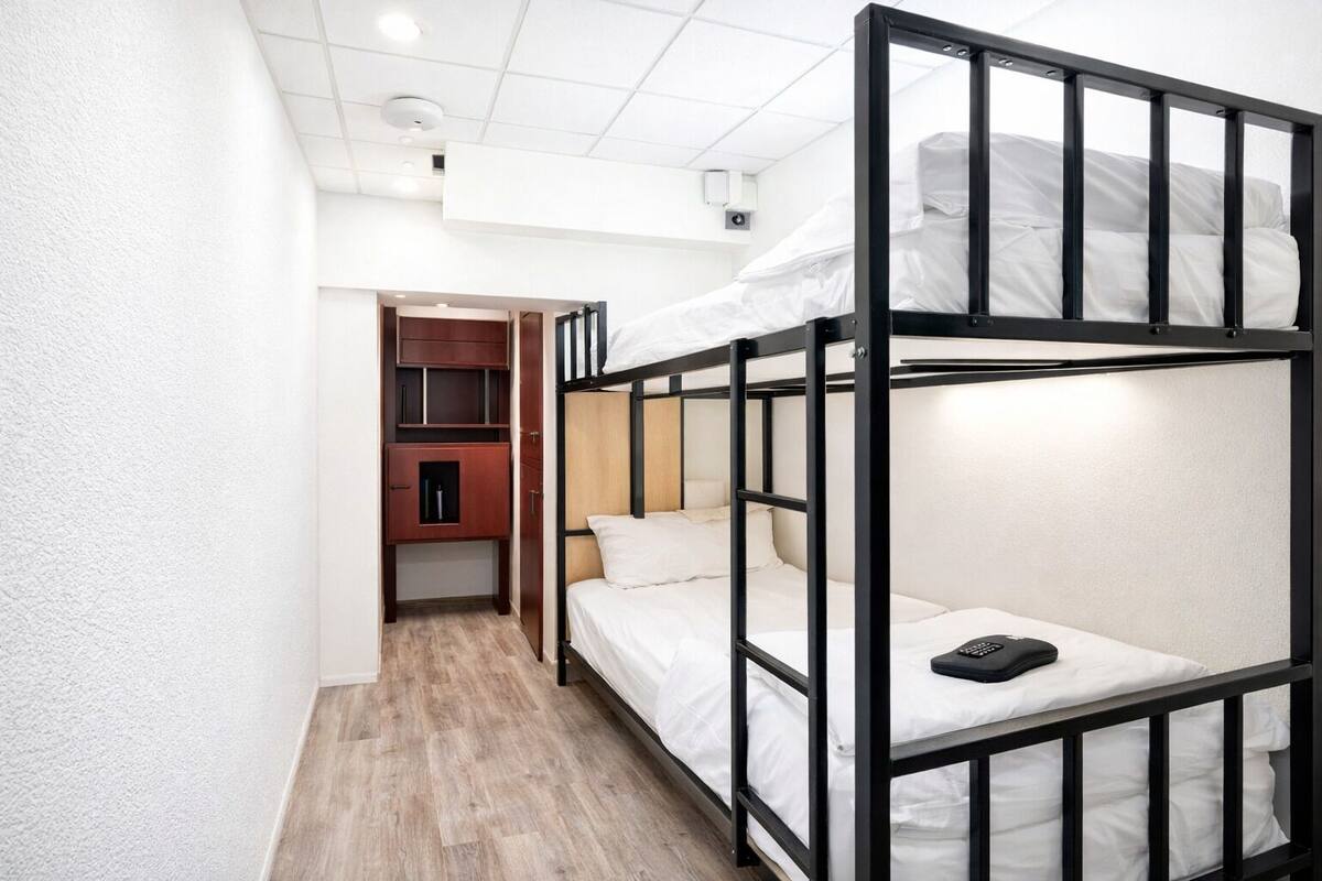 A bunk bed room with a wooden wardrobe and a small cabinet.