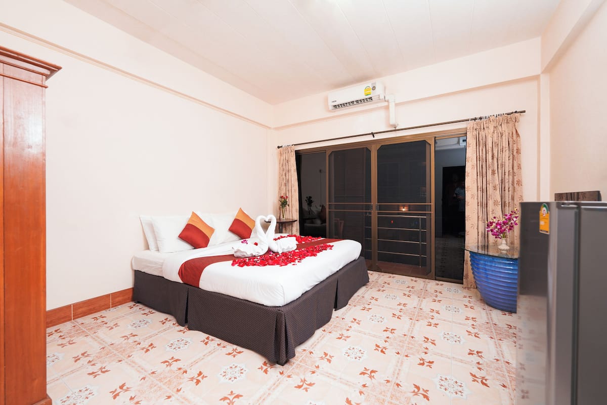 A hotel room with a bed, a wardrobe, a bathroom, and a balcony.