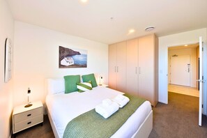 Habitación de hotel con cama, mesita de noche, un cuadro y armario.