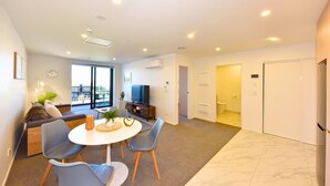 Una sala moderna con comedor, un sofá, un televisor y vistas al exterior.
