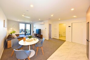 A modern living room with a dining area, a sofa, a TV, and a view to the outside. - Fresh 1BR City Base on Manchester (Christchurch)