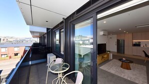 A modern apartment with a balcony, a kitchen, and a living area with a TV and seating. - Fresh Build City Retreat in Christchurch CBD (Christchurch)