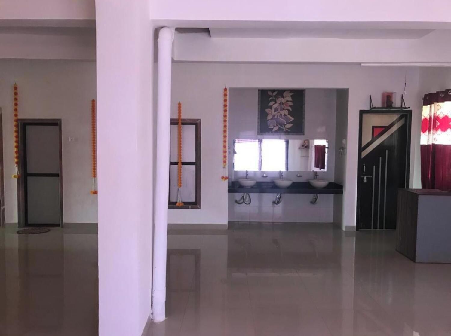 A spacious room with a large window, a sink area, and a door.