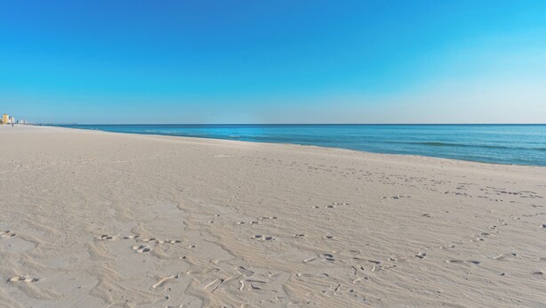 A sandy beach with footprints leading to the water. - PCB Condo Near Pier Park + Pool + Pickleball Court | Beachwalk 10B by AvantStay (Panama City Beach)