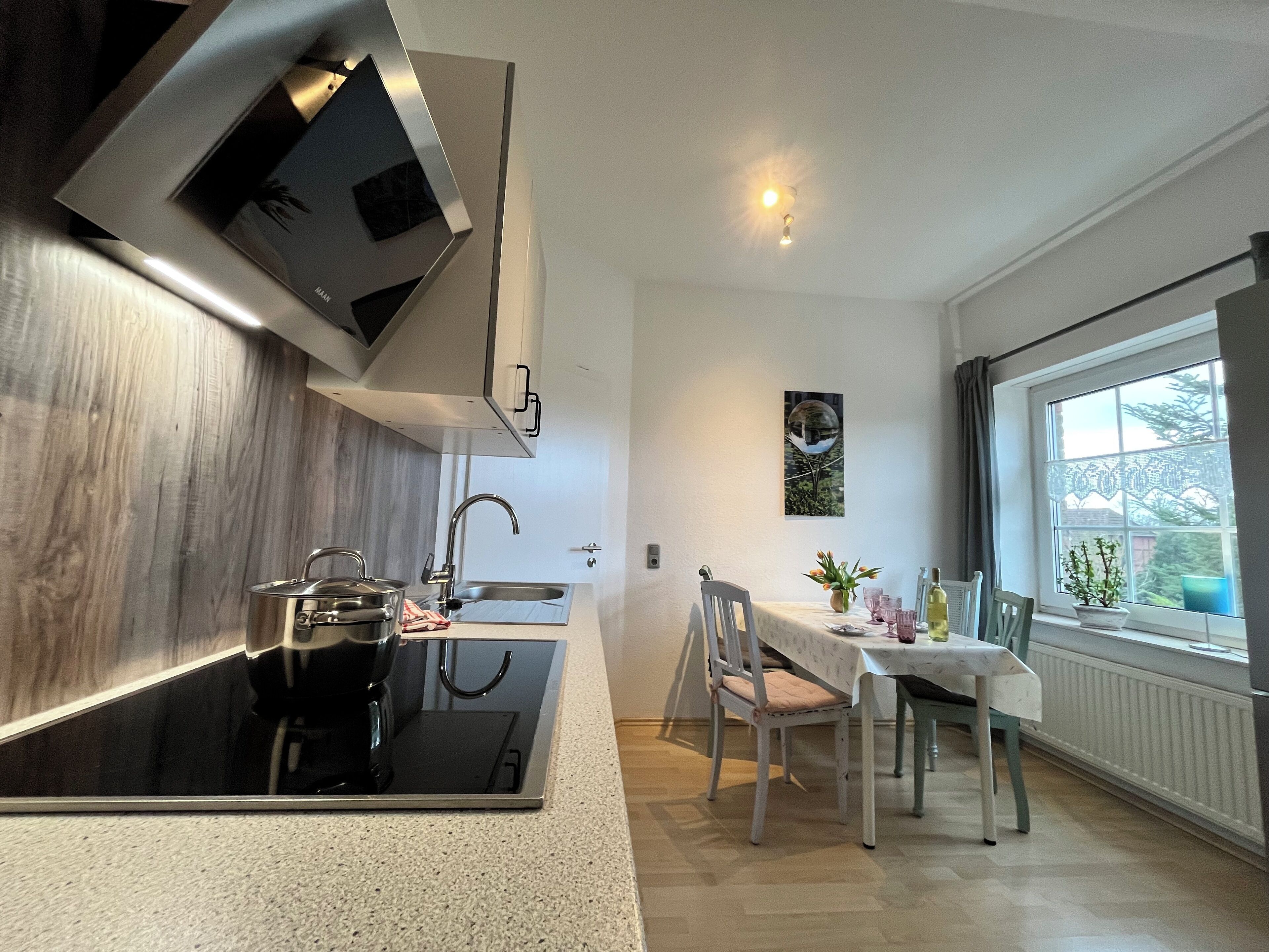 A modern kitchen with a built-in stove, a sink, and a dining area with a table and chairs.