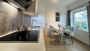Une cuisine moderne équipée d’une cuisinière intégrée, d’un évier et d’un coin repas avec une table et des chaises.