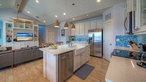 Una cocina moderna con una isla central, electrodomésticos de acero inoxidable y una zona de comedor con un sofá.