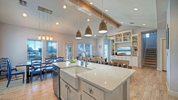 Una cocina amplia con una isla grande, suelo de madera e iluminación colgante.