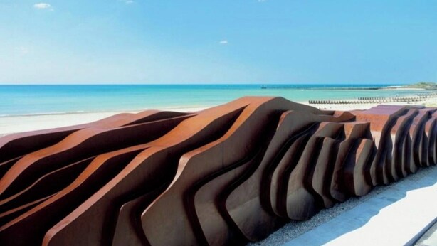 Una playa con una característica arquitectónica ondulada y singular al frente.