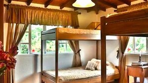 A bunk bed room with a wooden ceiling and a window with curtains. - El Oasis Organic Farm (Piedecuesta)