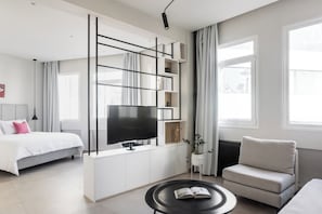 A modern living room with a large flat-screen TV, a sofa, a coffee table, and a bed. - Plaka Stylish & Fully Equipped Apartment - PB2A (Athens)