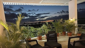 A rooftop terrace with potted plants, outdoor furniture, and a view of the sky. - Luxurious 3-Bedroom Apartment in Juan Dolio with Pool Access (Juan Dolio)