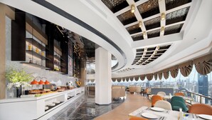 A modern hotel lobby with a buffet, seating areas, and a city view. - Hampton by Hilton  Hubin South Road (Xiamen)