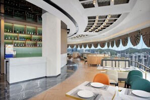 Eine moderne Hotelhalle mit Bar, Sitzgelegenheiten und Blick auf die Stadt.