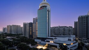 A high-rise hotel with a prominent dome and 'Champion' signage, surrounded by other tall buildings. - Hampton by Hilton  Hubin South Road (Xiamen)