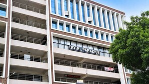 Un hotel de varios pisos llamado 'HOTEL PARADISE', con balcones y un cartel que indica 'SHIBUAN HOTEL PARADISE'.