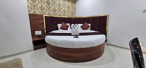 A circular bed with a wooden frame and a headboard with a gold trim. There are two pillows and a white towel on the bed. - Hotel Paradise (Ahmedabad)