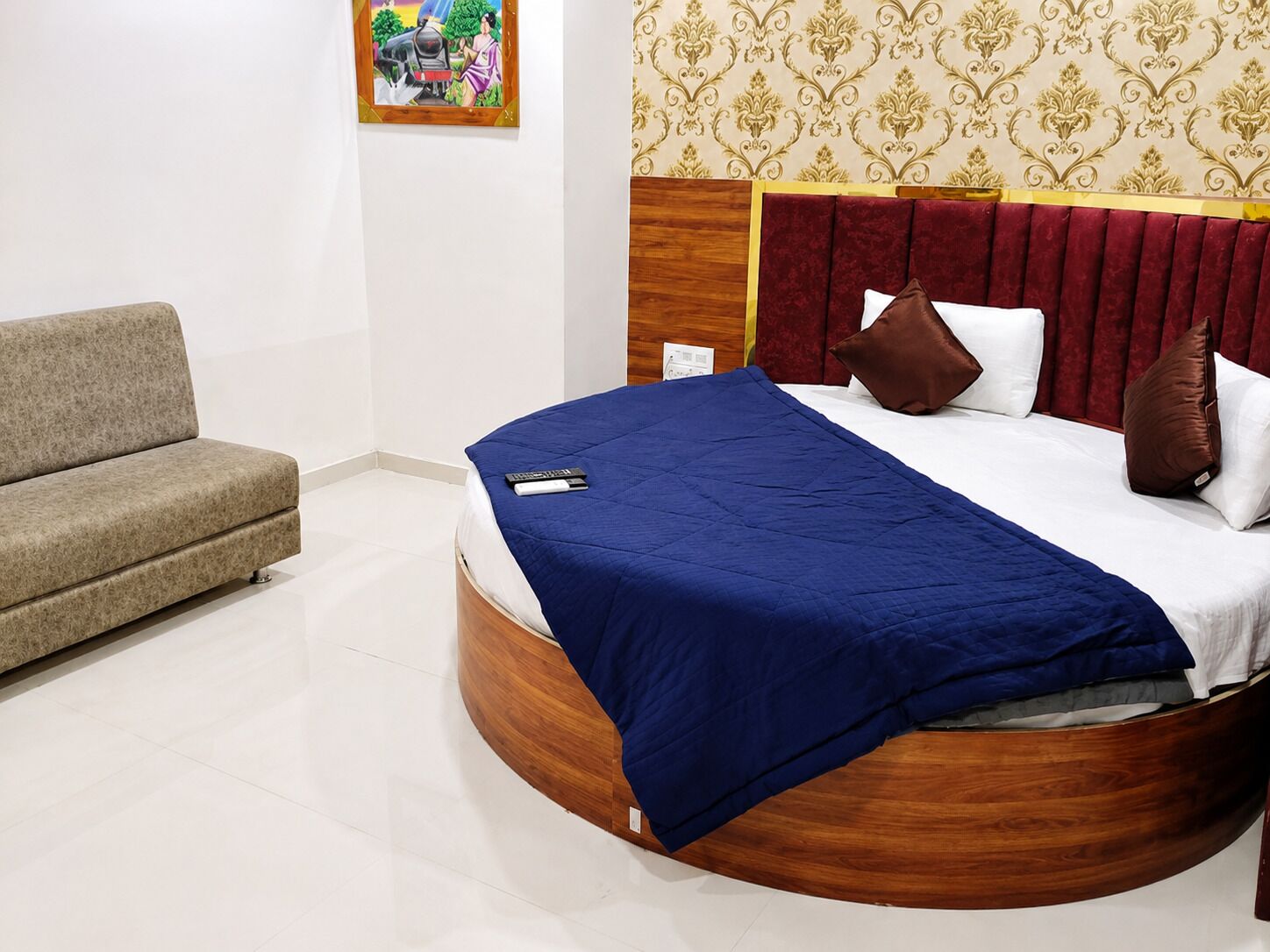 Um quarto com uma cama curva, um sofá e um quadro na parede.