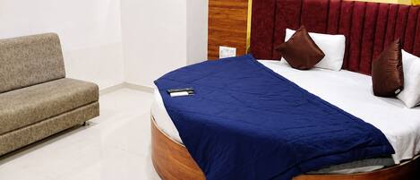 Um quarto com uma cama curva, um sofá e um quadro na parede.