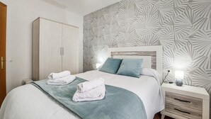 A neatly made bed with two pillows, a bedside table with a lamp, and a wardrobe. - Lovely home in Benaojan with swimming pool (Benaojan)