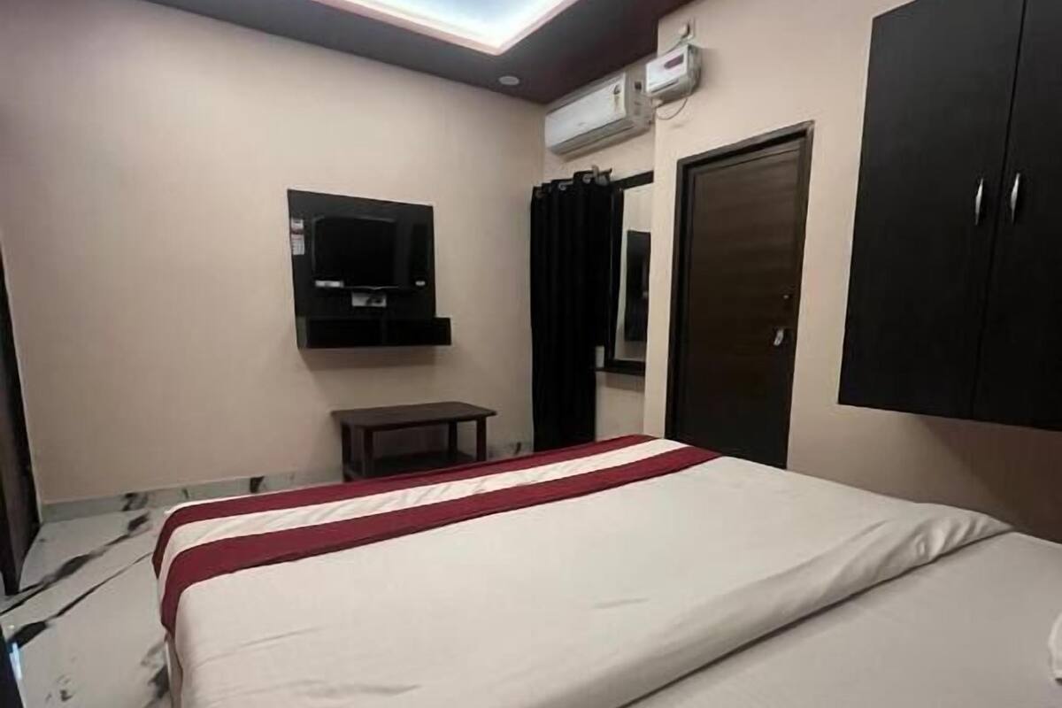 Una habitación de hotel con cama, televisión montada en la pared, aire acondicionado y armario.