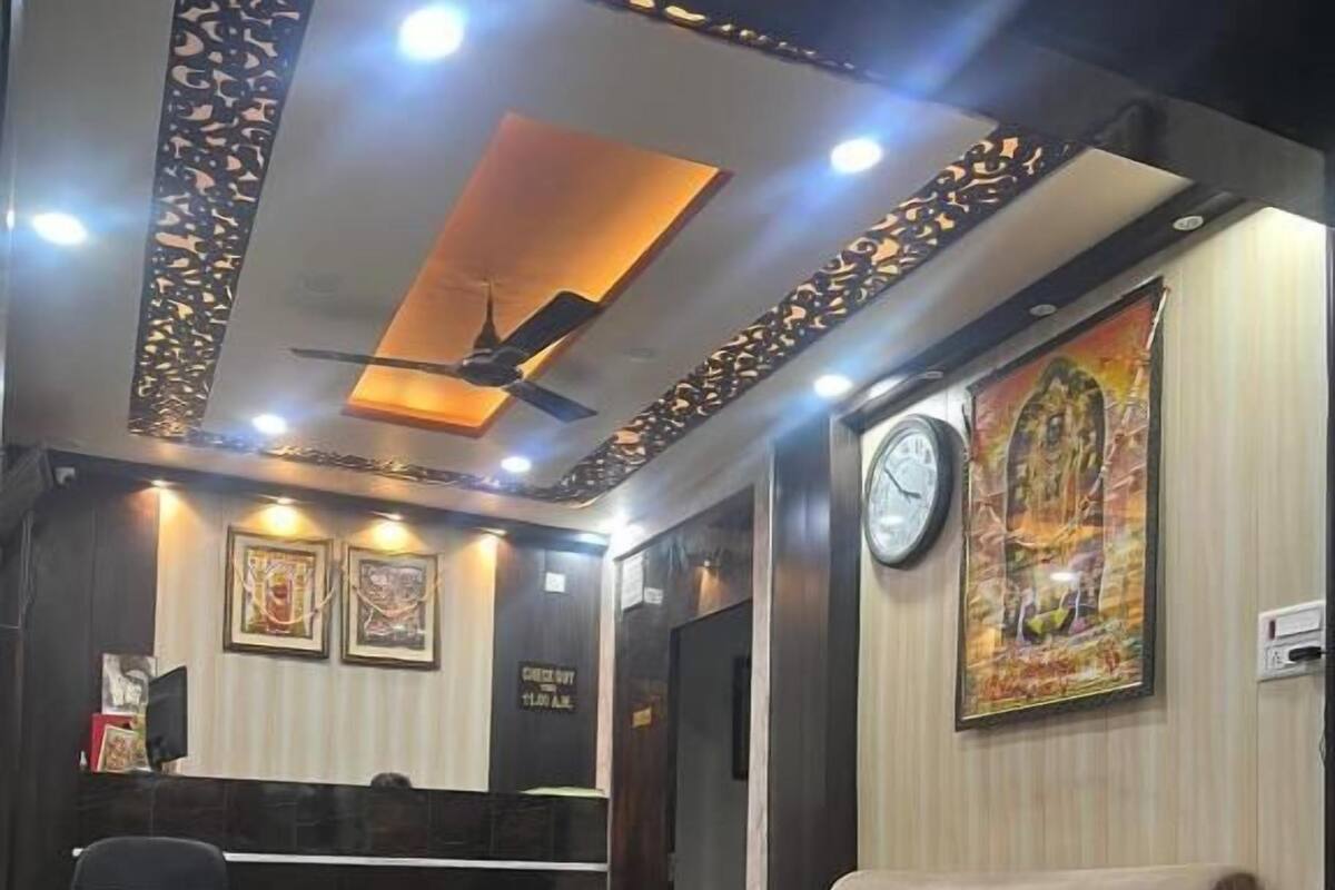 Un área de recepción con un sofá, una silla, una mesita, un reloj y cuadros en la pared.